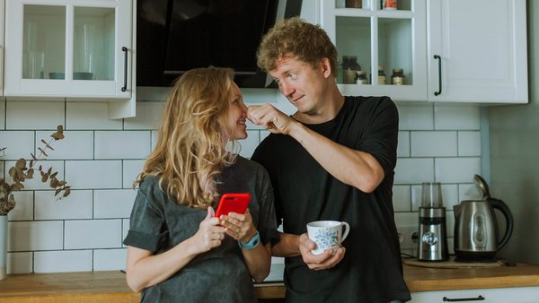 Smějící se žena a muž stojící v kuchyni – společný účet
