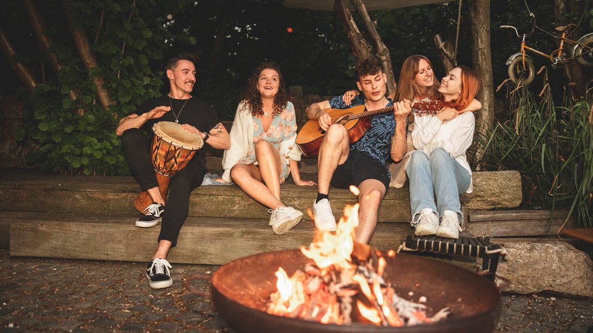 Mladí lidé sedící u táborového ohně – vanlife dobrodružství