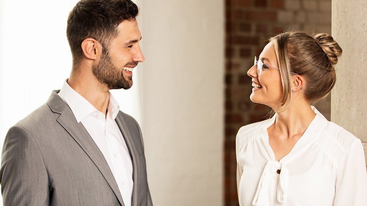 Muž a žena se usmívají a mluví v profesionálním prostředí.