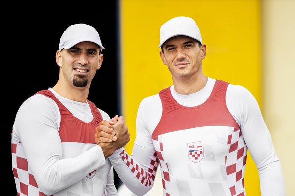 Dva muži v ladících sportovních oblečeních si podávají ruce.