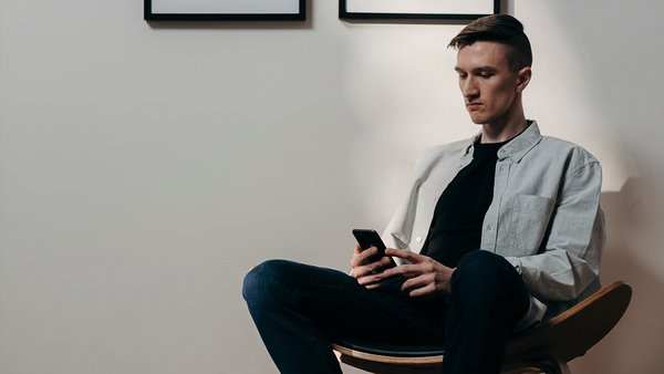 Muž se úzkostlivě dívá na svůj mobilní telefon – zdražování Muž se úzkostlivě dívá na svůj mobilní telefon – zdražování