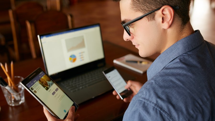 Osoba používající notebook a mobilní telefon u stolu