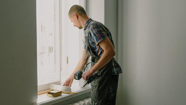 Muž opravuje okno – soukromé pojištění pracovní neschopnosti