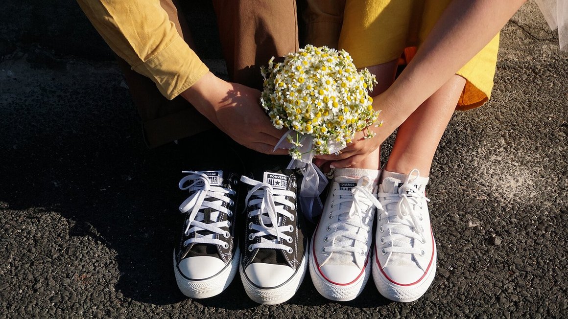 Pár sedící na zemi s kyticí v rukou – plánování svatby