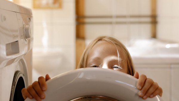 Dívka před pračkou – snižte náklady na energie