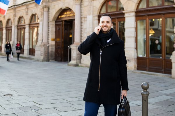 Muž stojící venku a telefonující.