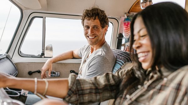 Mladý pár s úsměvem za volantem – pojištění karavanu