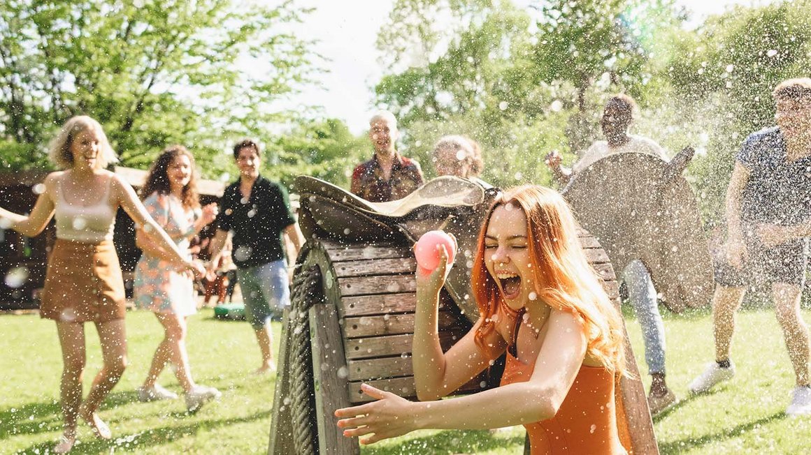 Žena skrývající se během vodní bitvy skupiny mladých lidí