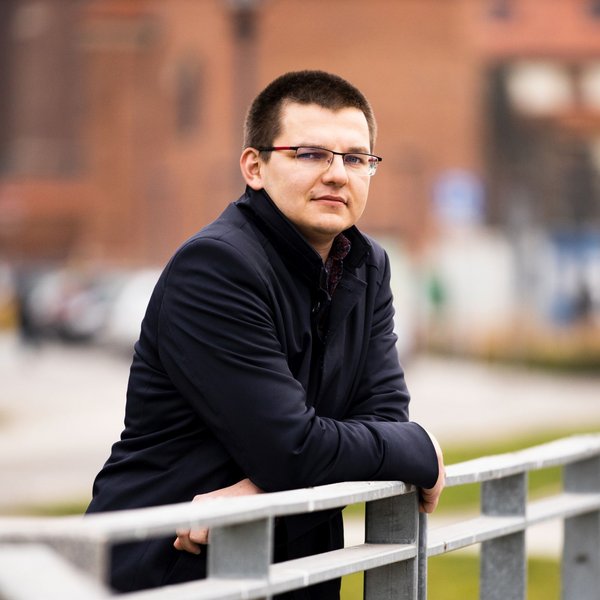 Muž opírající se o zábradlí venku.