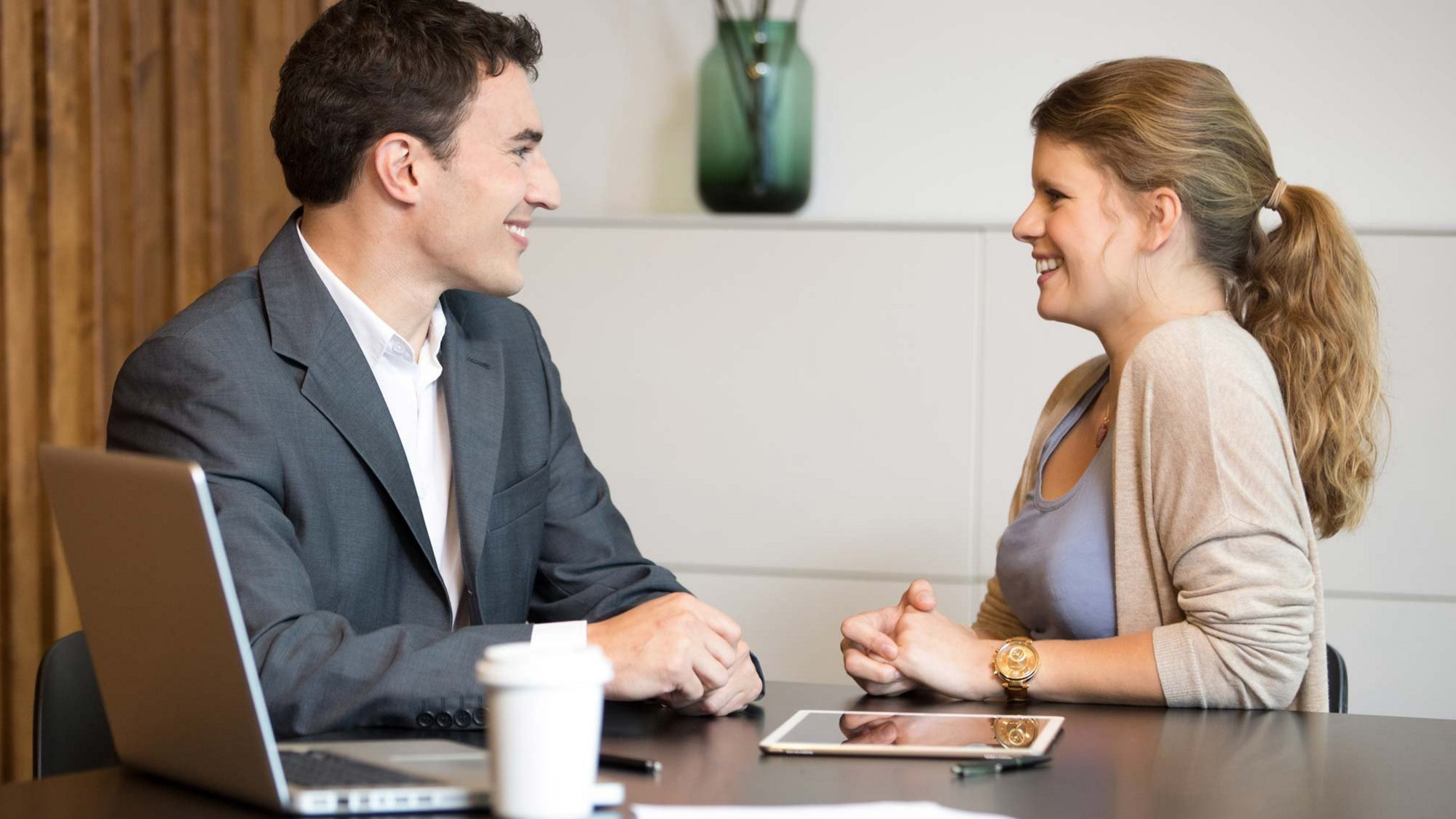 Muž a žena sedí u stolu a usmívají se.