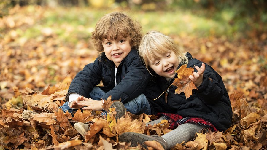 Dvě děti sedící v podzimním listí