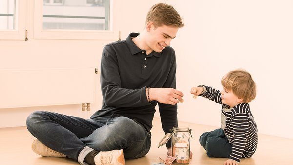Dítě a mladý muž spoří peníze ve sklenici Dítě a mladý muž spoří peníze ve sklenici