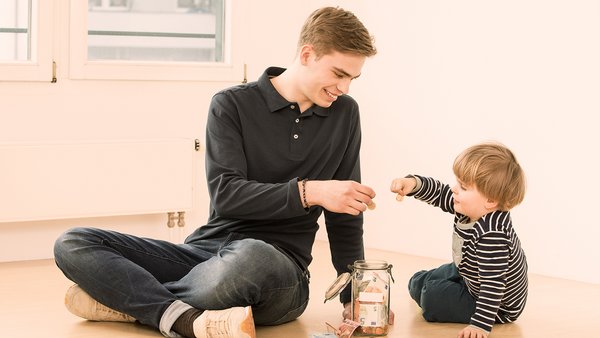 Dítě a mladý muž spoří peníze ve sklenici 