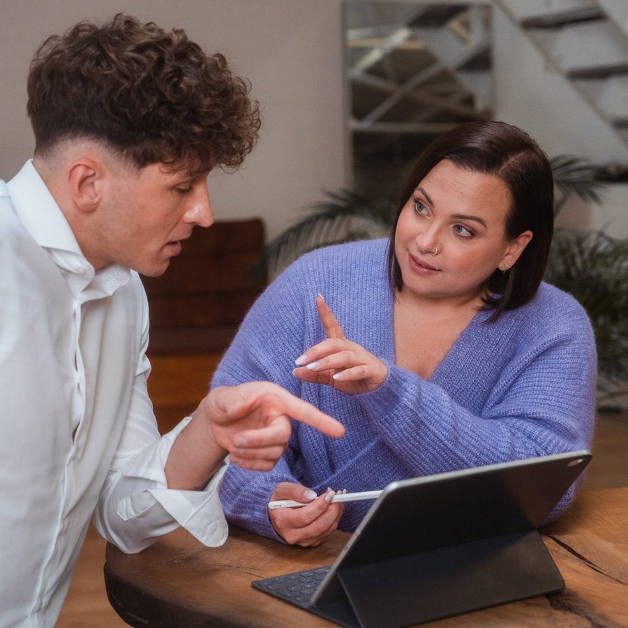 Dva lidé diskutující o finančních informacích u stolu s tabletem.