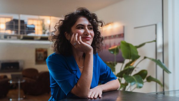 Žena sedící u stolu v interiéru, zamyšlená v pracovním prostředí