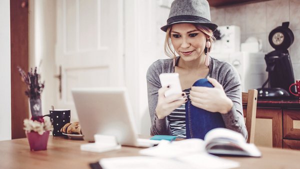 Mladá žena u stolu s chytrým telefonem, notebookem a dokumenty pro vedení osobního rozpočtu