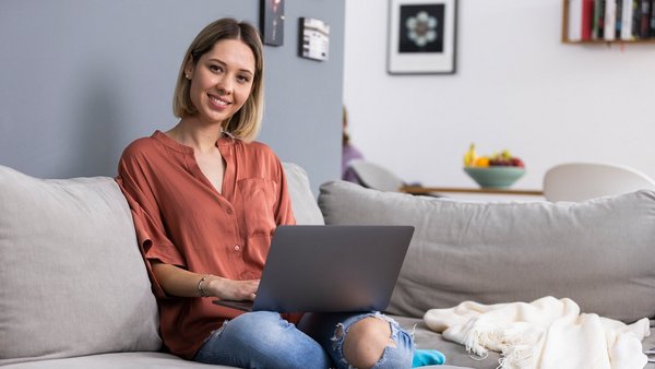 Žena s notebookem pracující z domova na gauči